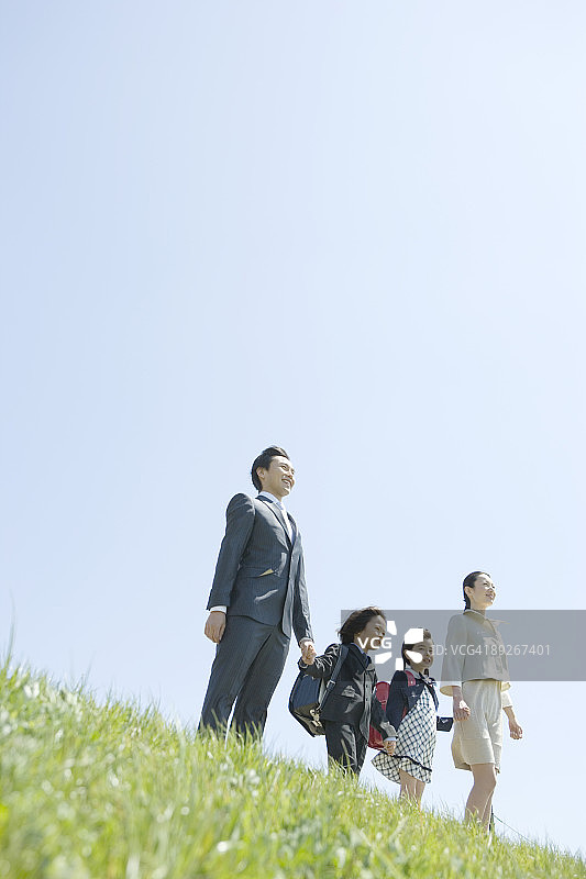 父母和两个孩子站在草坡上图片素材