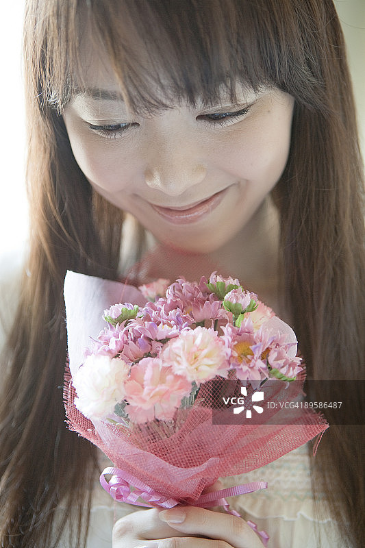 年轻女人抱着一束鲜花，面带微笑图片素材