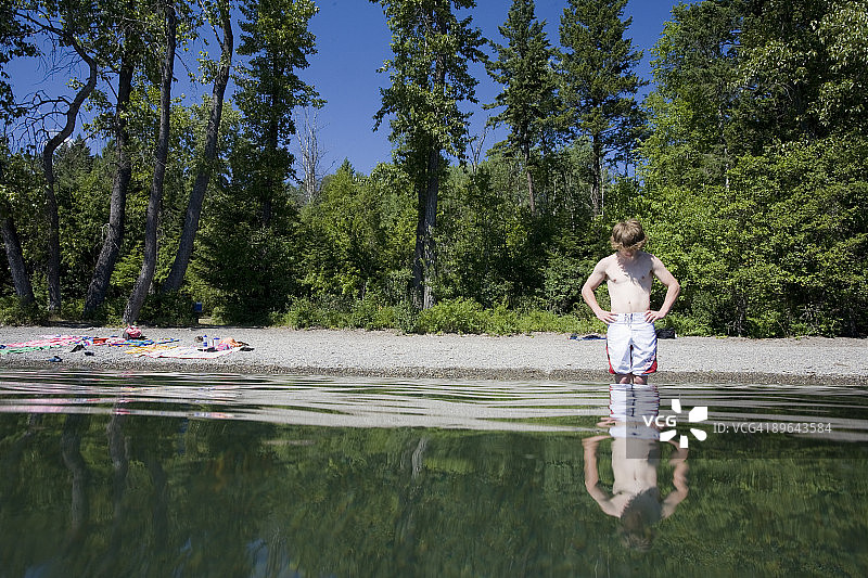 在湖中审视自己倒影的年轻人图片素材