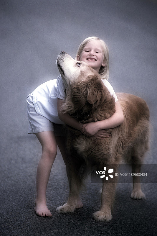 笑容满面的女孩拥抱金毛猎犬图片素材