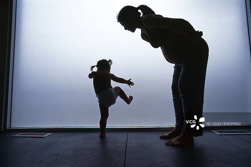 怀孕母亲与跳舞女儿的剪影图片素材