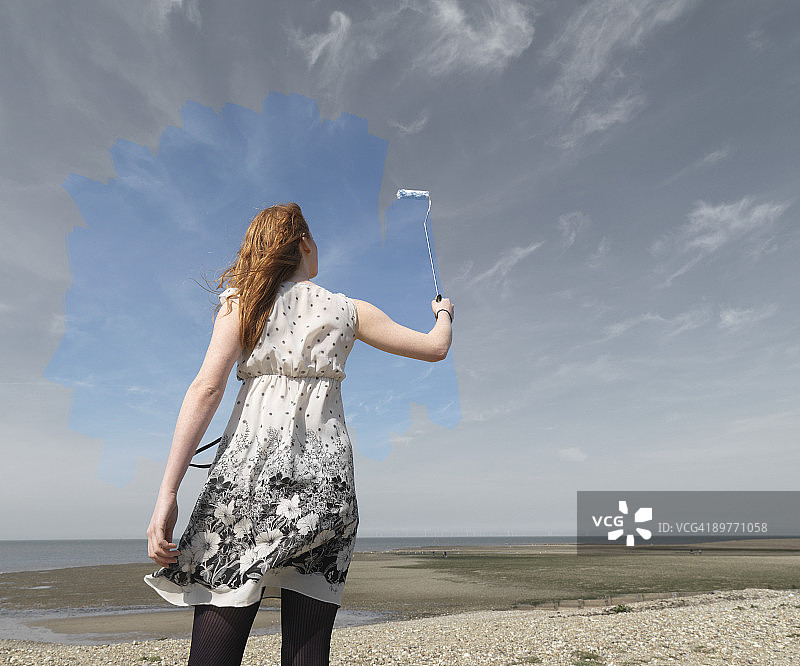 年轻女子在画灰蓝色天空图片素材