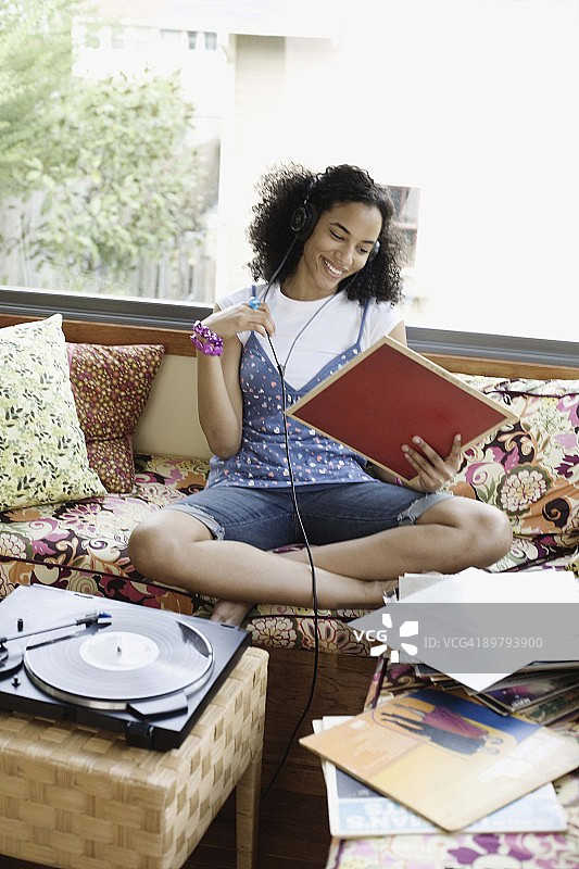 少女戴着耳机在室内听音乐看唱片图片素材