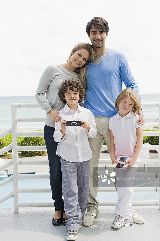 和孩子们站在栏杆旁边的情侣图片素材