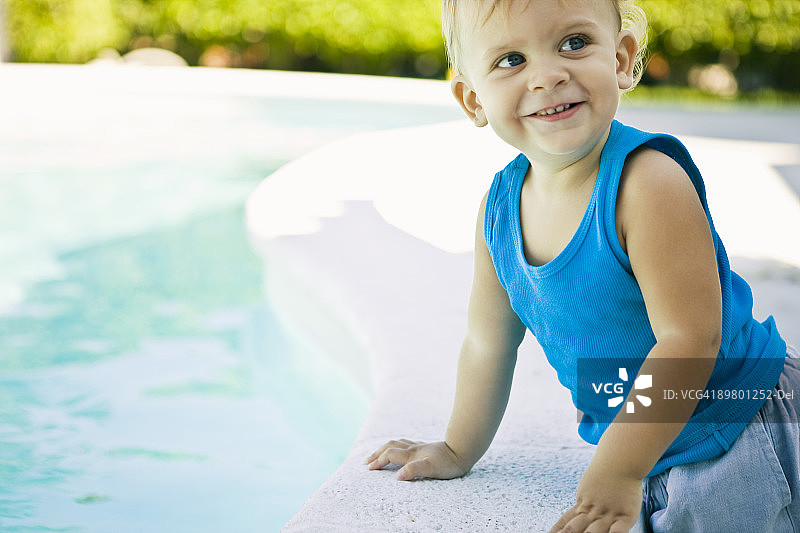 在泳池边靠在壁架上的男婴图片素材