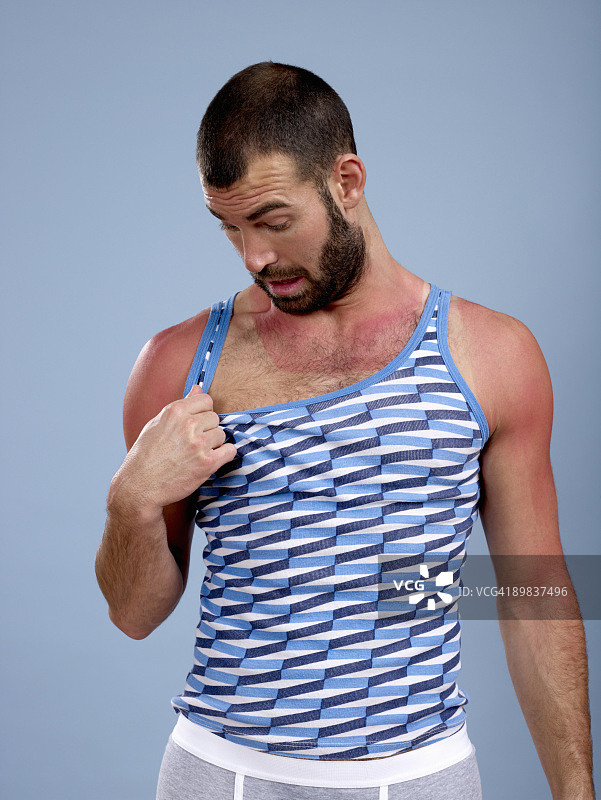 男子查看自己晒伤的胸部图片素材