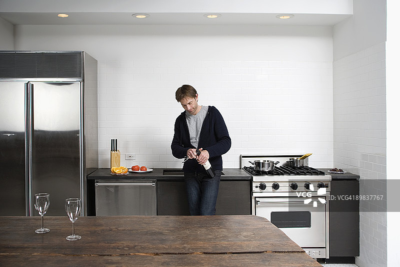 男子在厨房打开一瓶葡萄酒图片素材