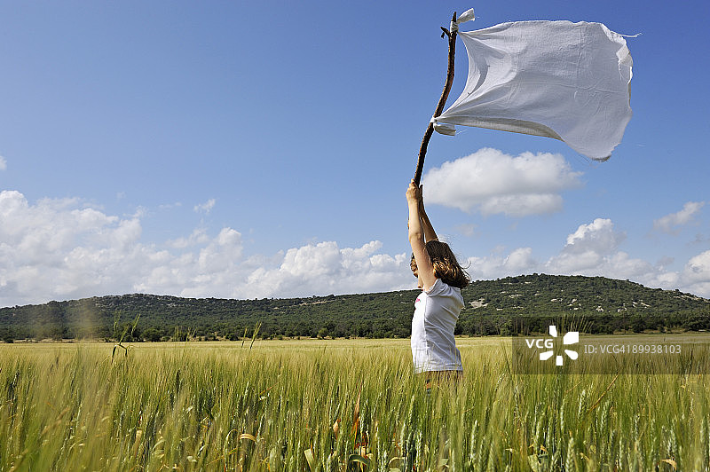 在麦田里高举白旗的女孩图片素材