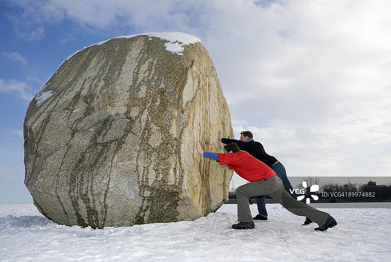 两名男子推动巨大的巨石图片素材