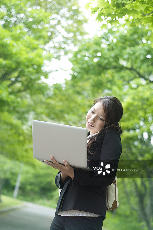 商务女性使用笔记本电脑和手机图片素材