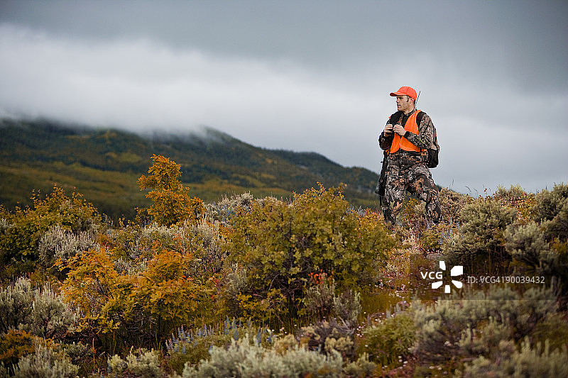 猎人手持望远镜和步枪向外观察图片素材