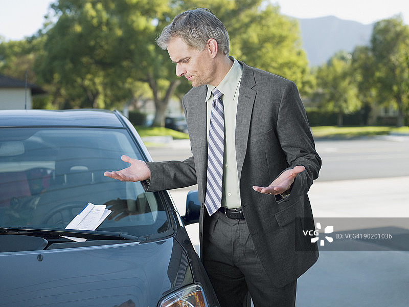 查看挡风玻璃上停车罚单的沮丧商人图片素材