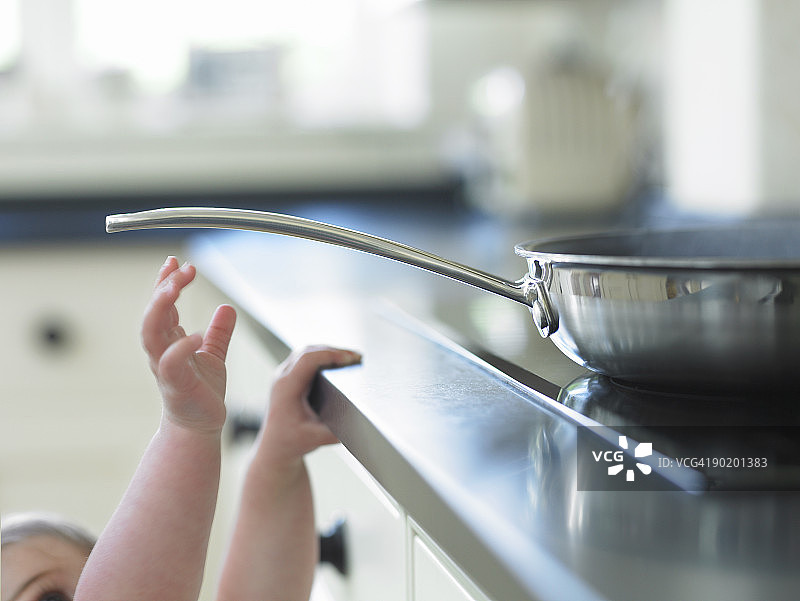 婴儿伸手拿炉子上滚烫的煎锅图片素材