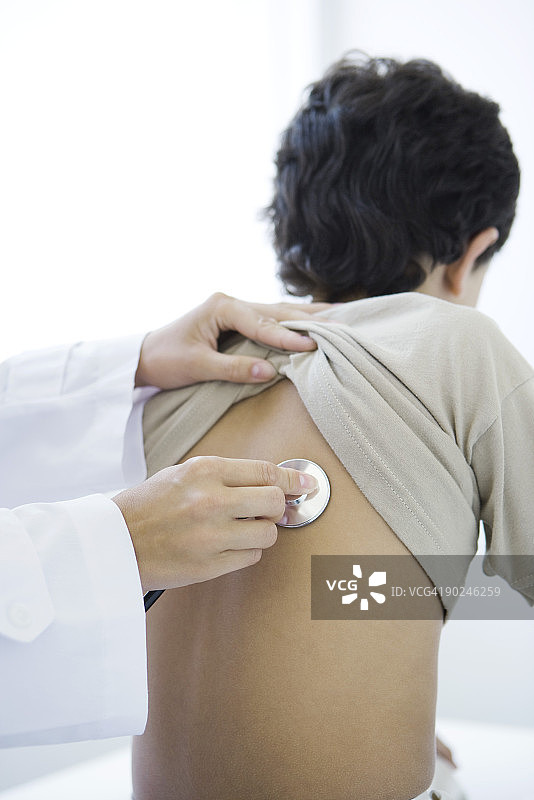 医生将听诊器放在男孩背上（局部视图）图片素材