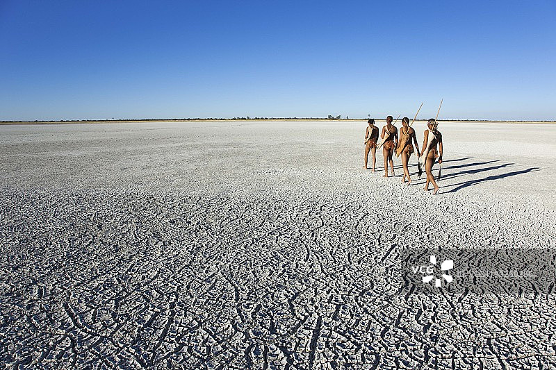 在博茨瓦纳马卡迪卡迪盐沼中行走的布须曼人图片素材