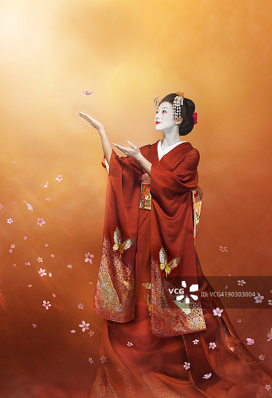 身穿红色和服的艺伎在捕捉樱花图片素材