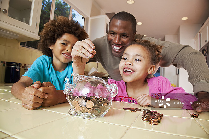 非洲父亲看女儿往储蓄罐里放硬币图片素材