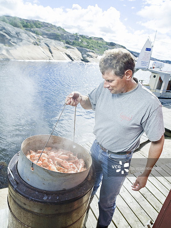 男人在瑞典煮挪威海螯虾图片素材