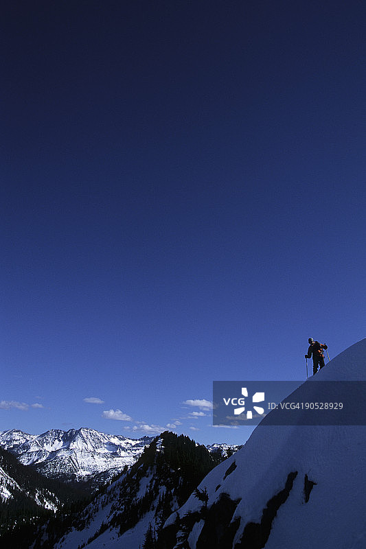 在华盛顿州史蒂文斯山口的喀斯喀特山脉滑雪时停下来的男人图片素材