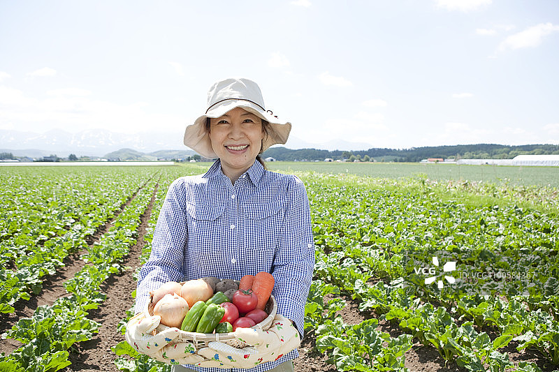 中年妇女在田野里拿着蔬菜图片素材
