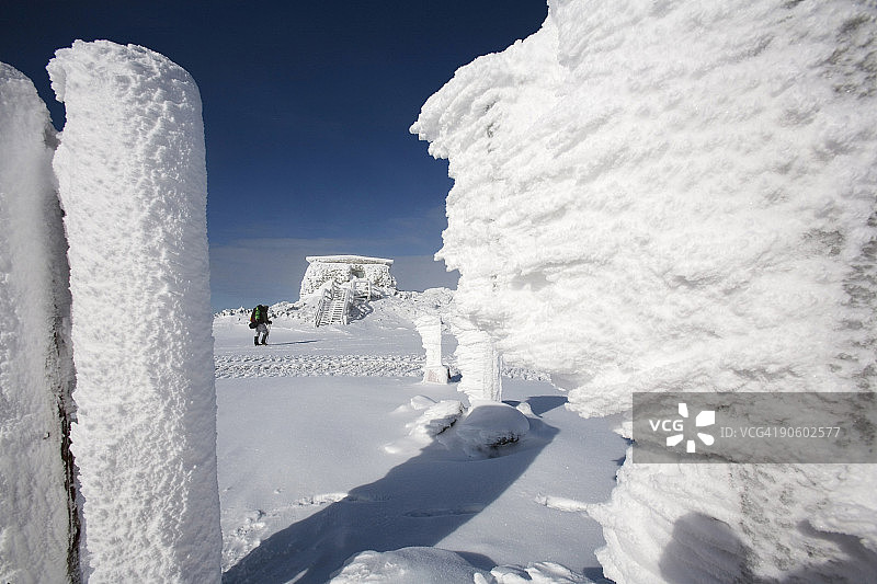 一名男子在华盛顿山顶的冰雪覆盖的建筑物之间徒步旅行图片素材