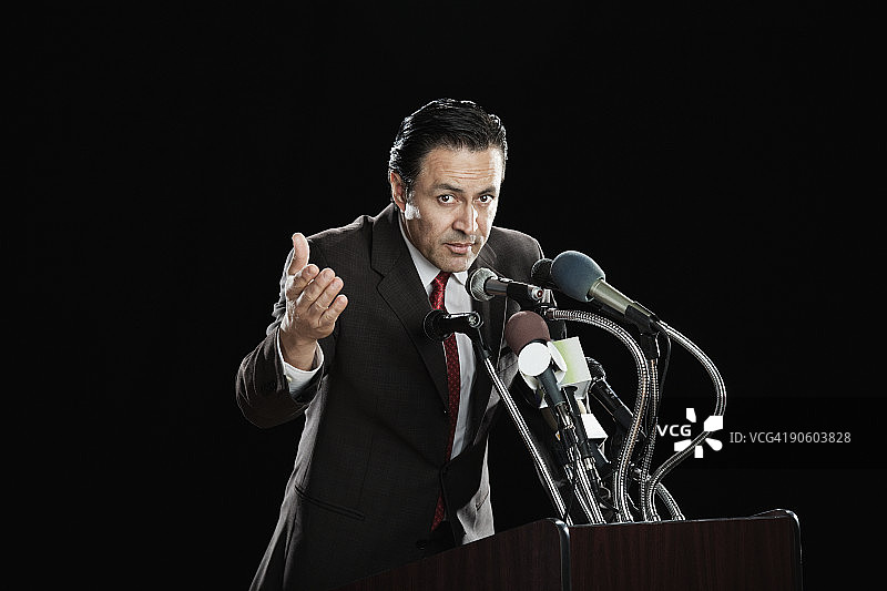 在带麦克风的讲台上做手势的西班牙裔男人图片素材