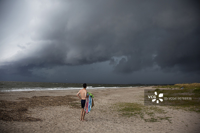 在海滩上眺望暴风雨天空的男人图片素材