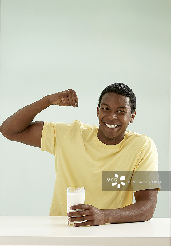 喝着牛奶展示肱二头肌的年轻男人图片素材