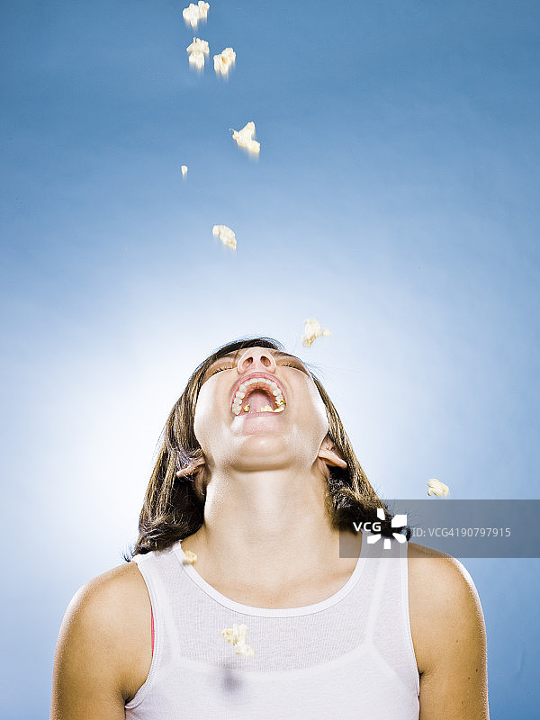 爆米花掉进年轻女人的嘴里图片素材