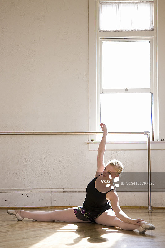 芭蕾舞者在舞蹈室地板上伸展图片素材