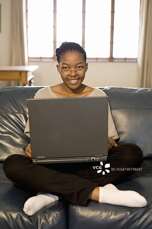 在沙发上使用笔记本电脑的年轻女子肖像，南非约翰内斯堡图片素材