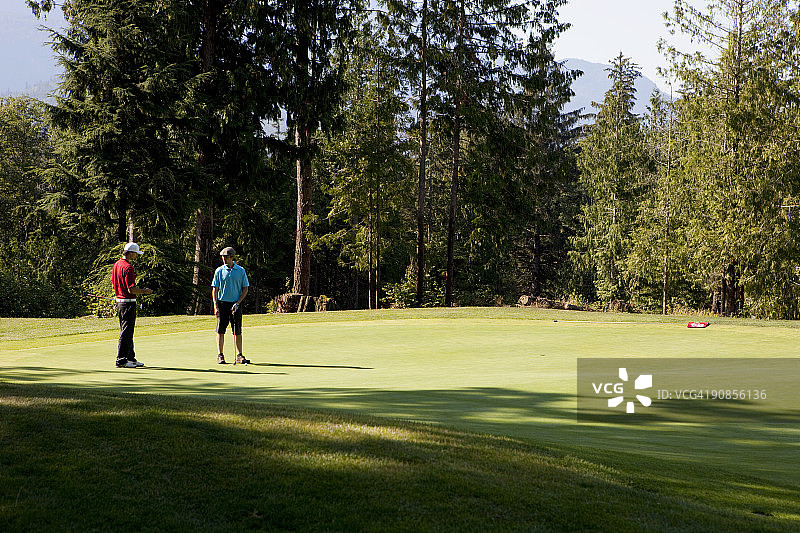 高尔夫球场上的男高尔夫球手和球童图片素材