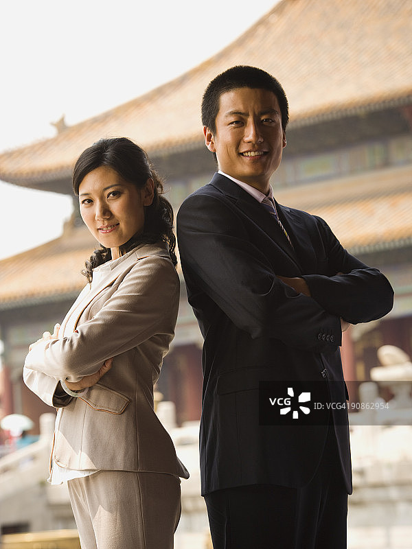 商人和女人背靠背站立，双手交叉，背景是宝塔图片素材