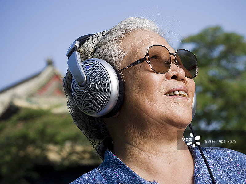 戴着耳机微笑的户外中年妇女图片素材