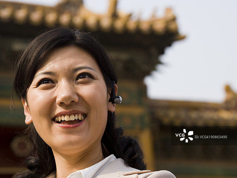 戴著耳机在户外微笑的女商人图片素材