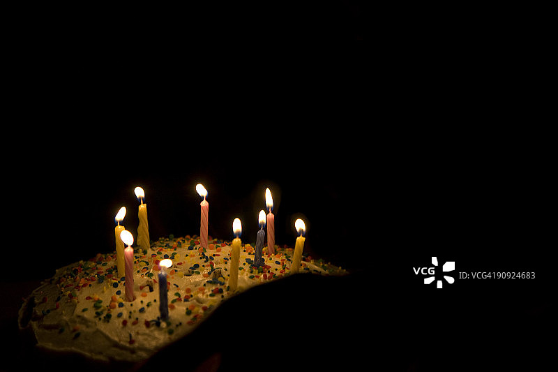 黑暗中生日蛋糕上的九根蜡烛图片素材