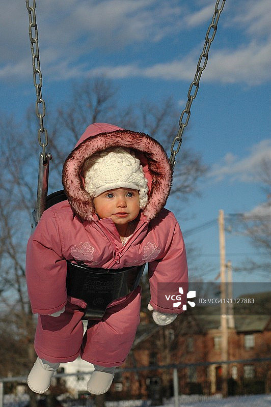 穿着滑雪服在秋千上的幼儿图片素材