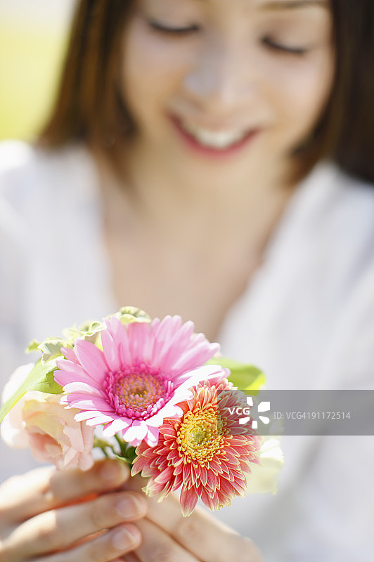 手持鲜花，前景对焦的女人图片素材