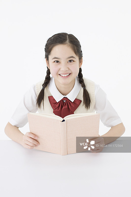 穿校服拿着书微笑的女孩图片素材