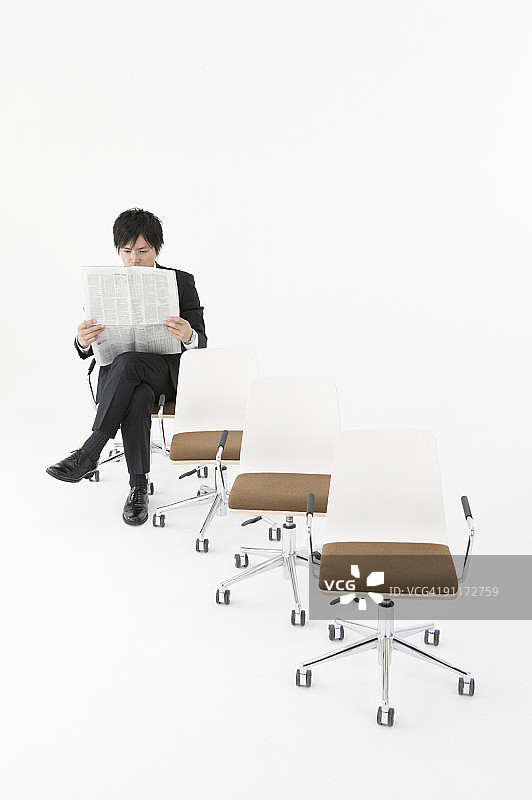 坐在椅子上看报纸的商人图片素材