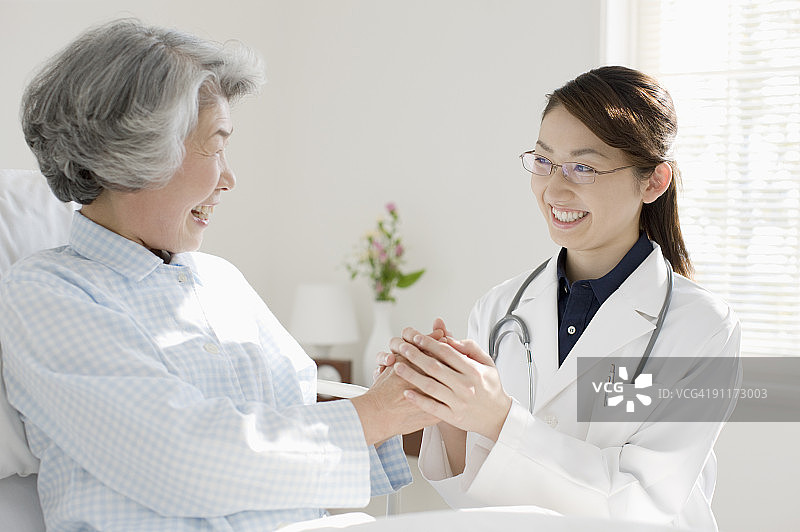 年轻女医生微笑握住病人的手图片素材