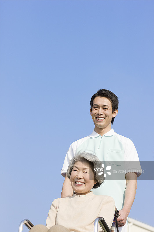 男护理员推着坐轮椅的老年妇女图片素材