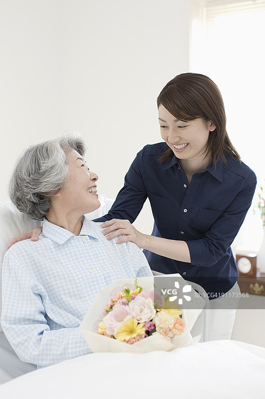 年轻女人和年长女人在床上相视而笑图片素材