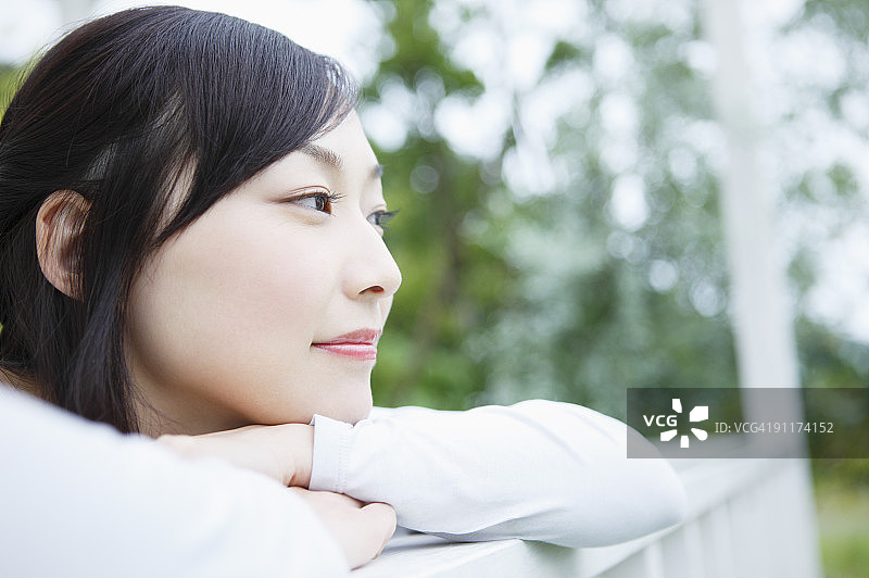 靠在阳台围栏上的年轻女人图片素材