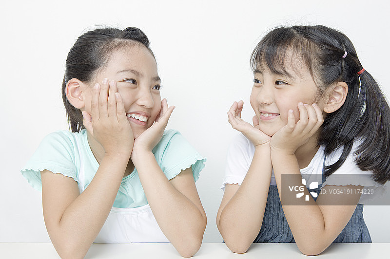 女孩们手托下巴，彼此微笑图片素材