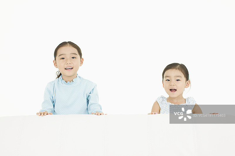 女孩们坐在沙发上，影棚拍摄图片素材