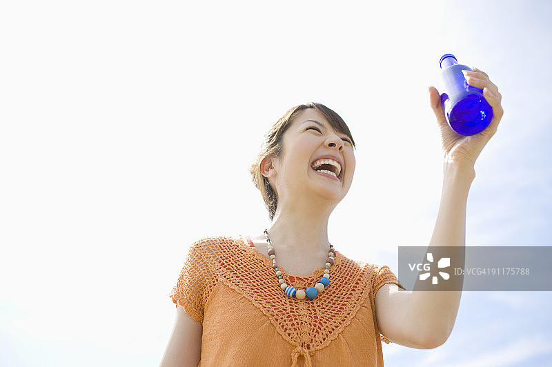 年轻女人拿着瓶子微笑图片素材