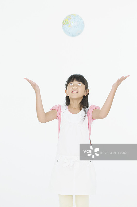 女孩向上抛地球仪的影棚照图片素材