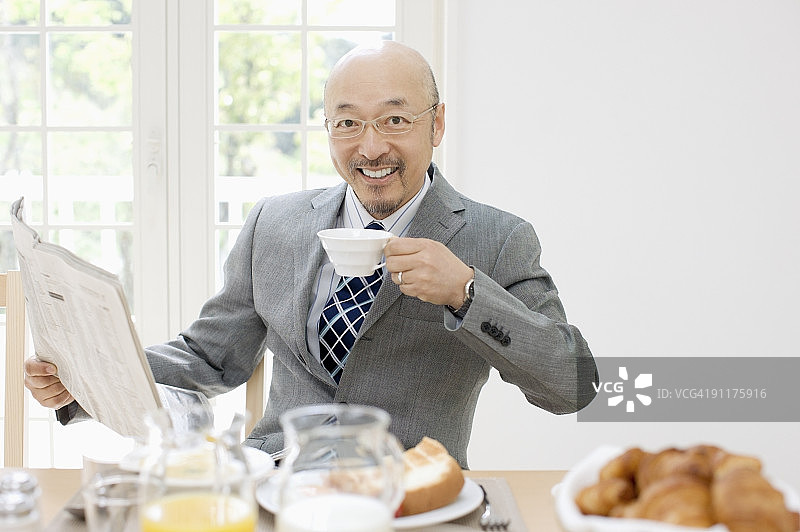 中年男人在吃早餐，读报纸图片素材