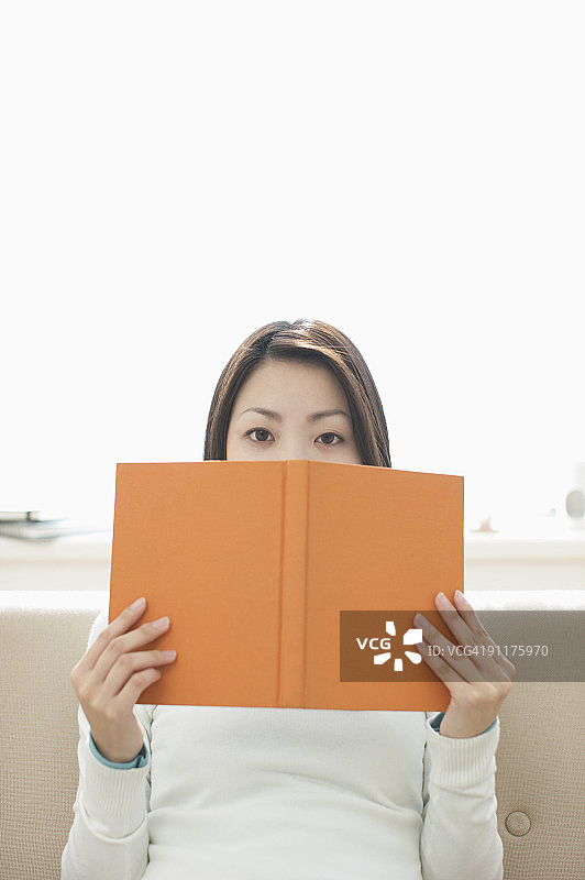 女人拿着书坐在沙发上图片素材